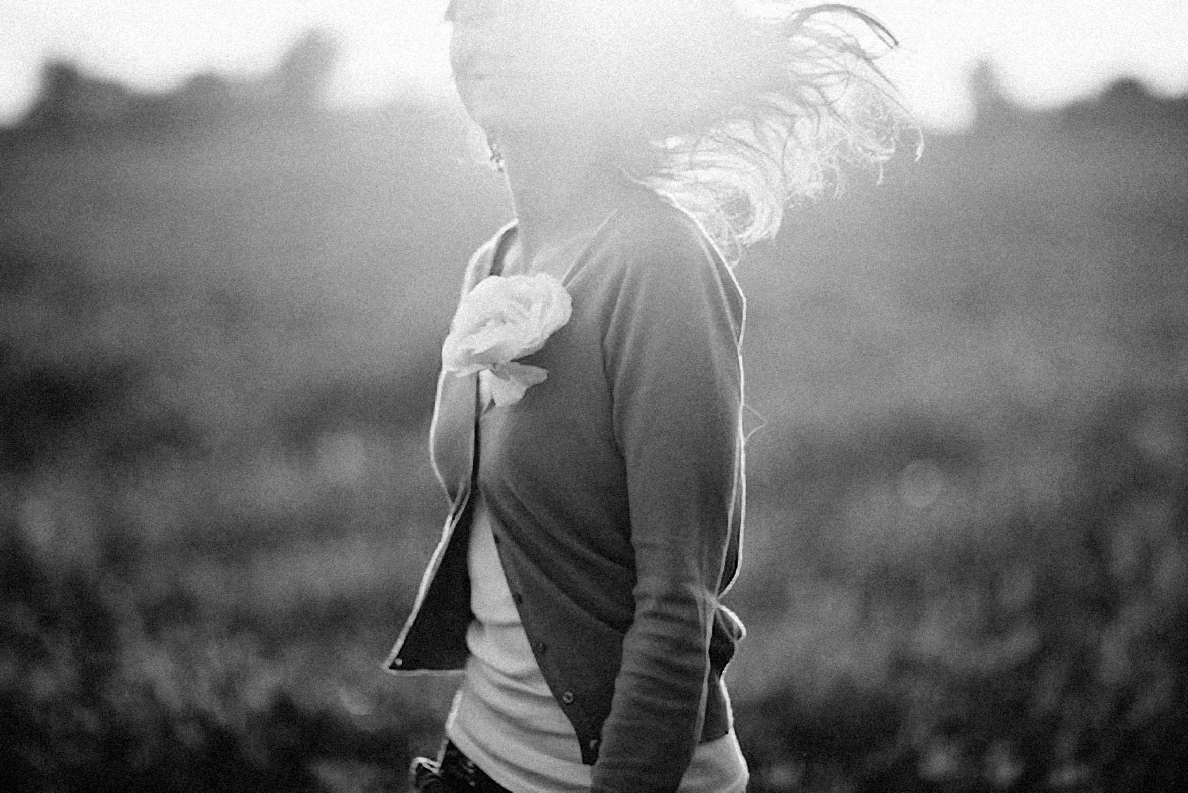 the back of a woman walking through a grass covered field