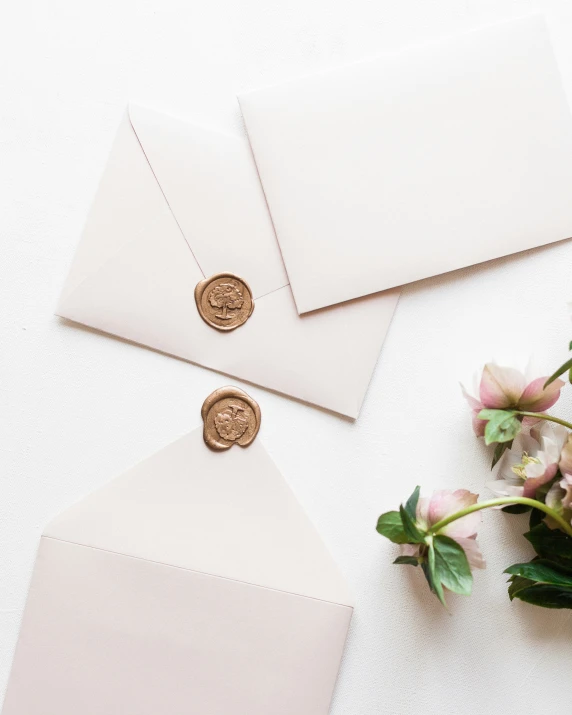 two wedding envelopes and a wax stamp are shown