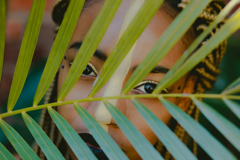  looking through palm leaves with eye - makeup