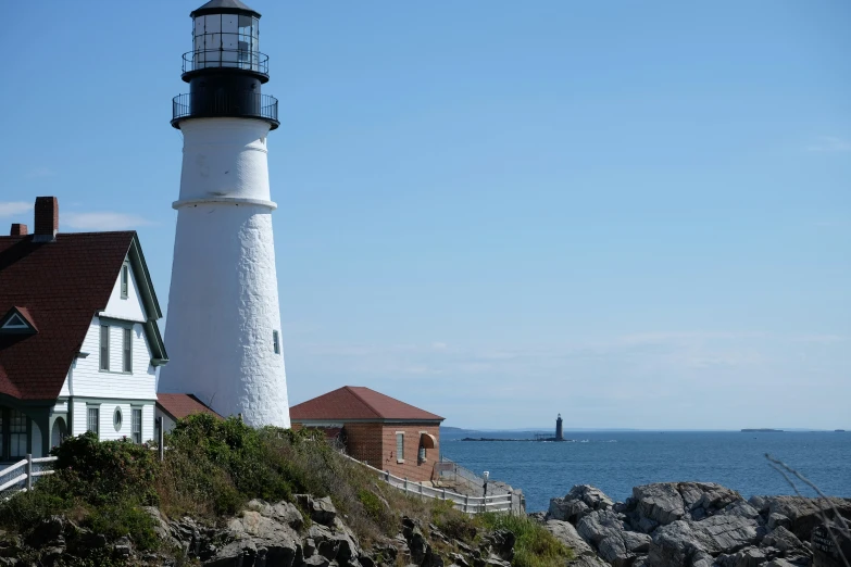 two houses on the rocky shore with a light house in the background