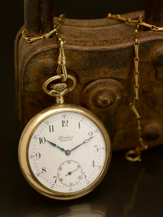 an antique gold clock necklace by a suitcase