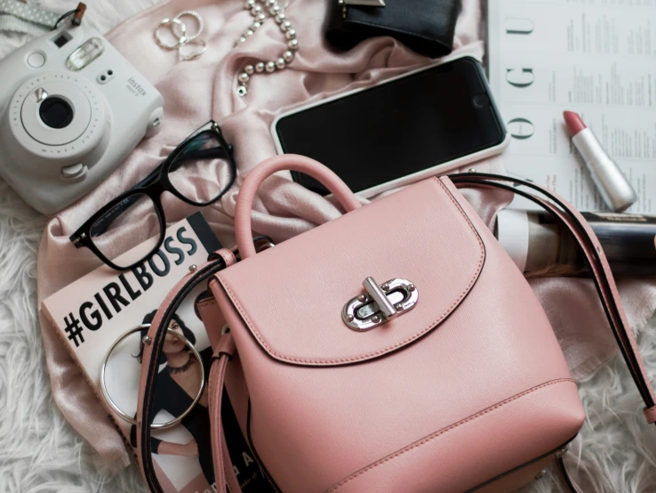 a small pink purse sitting on top of a bed