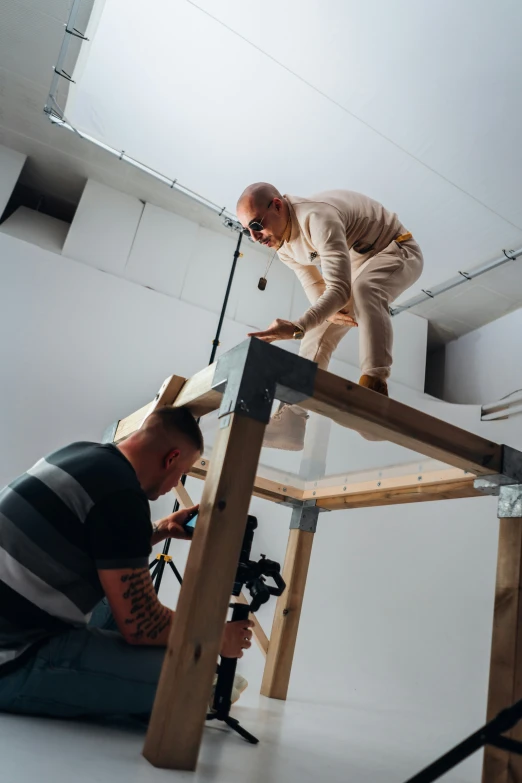 a man on top of a ladder standing up next to another man