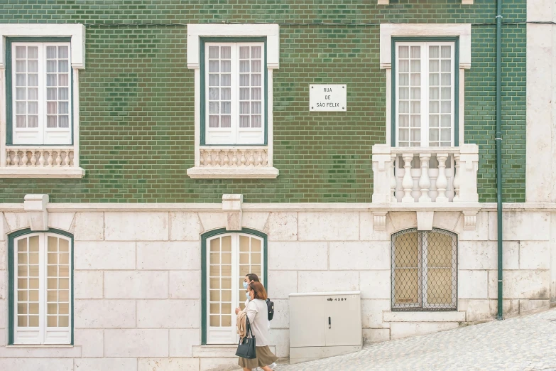 the woman is walking past the building while using her cell phone