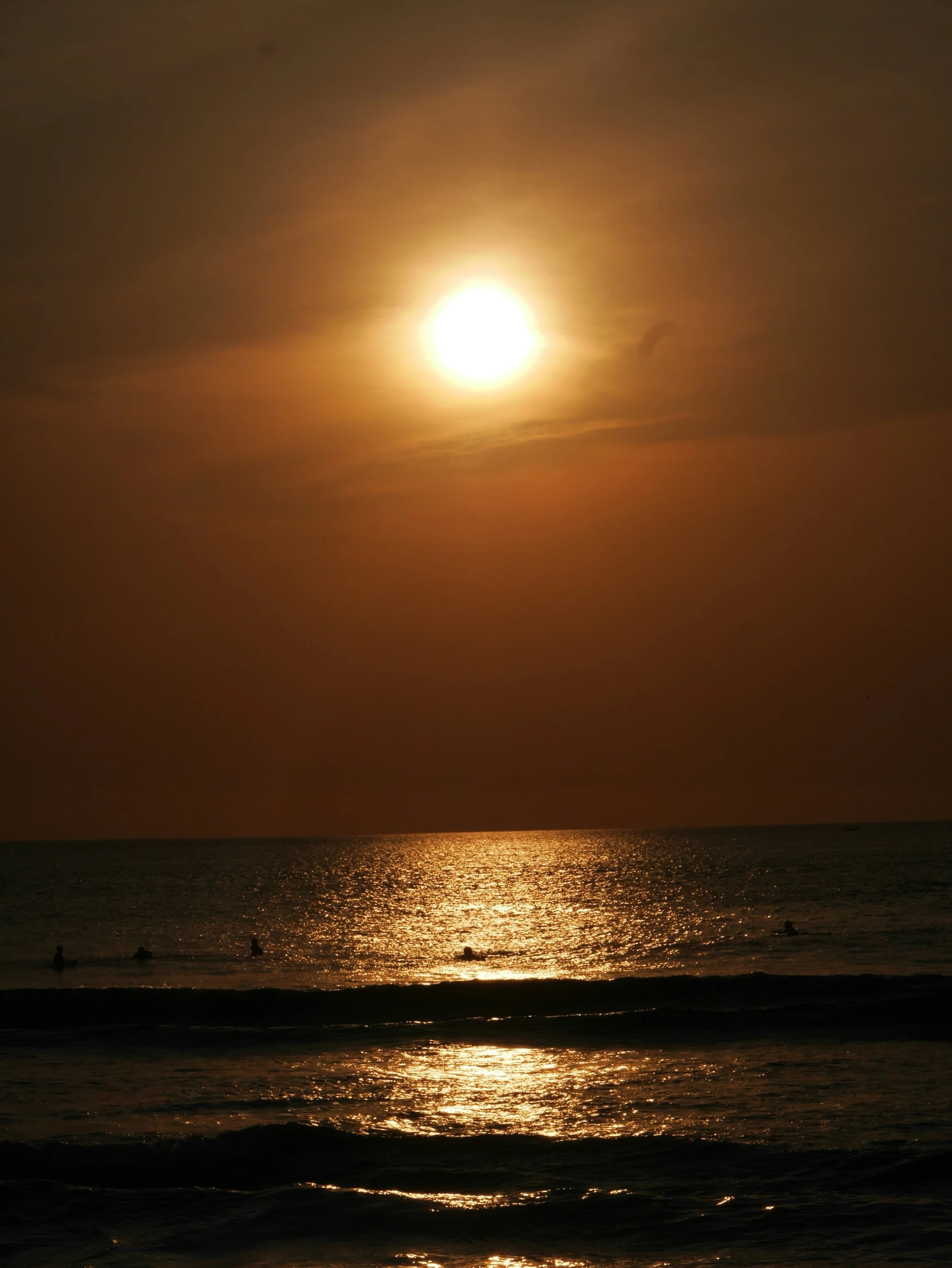 a large body of water with a sun in the background