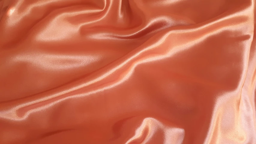 a peach satin fabric on a brown background