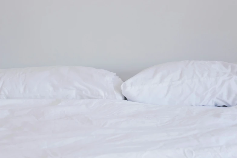 two pillows are sitting on top of a white bed