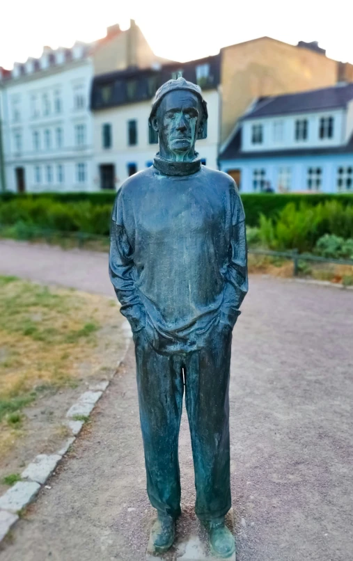 a statue of a man in a suit, standing on the sidewalk