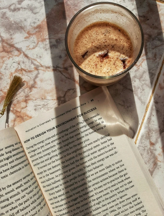 an open book sitting on top of a table next to a cup