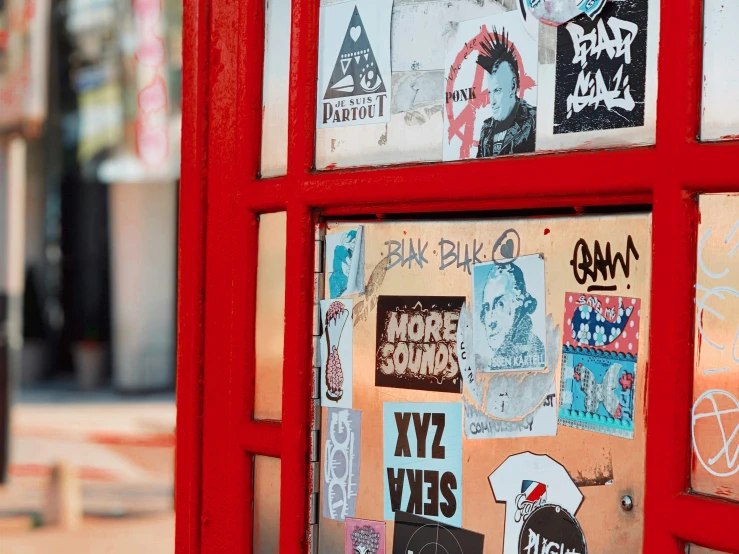 a red phone booth has many stickers on it