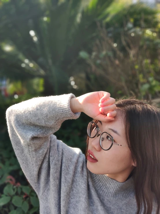 asian girl in a gray sweater is looking through her glasses