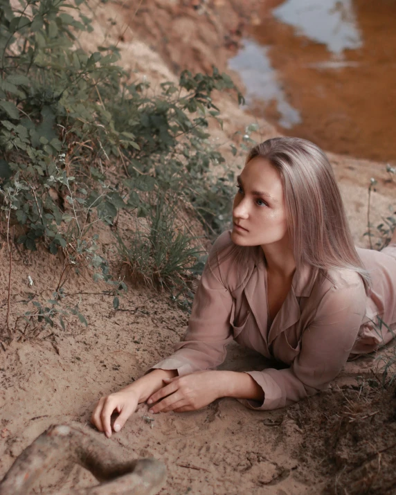 a woman sitting on the ground near water