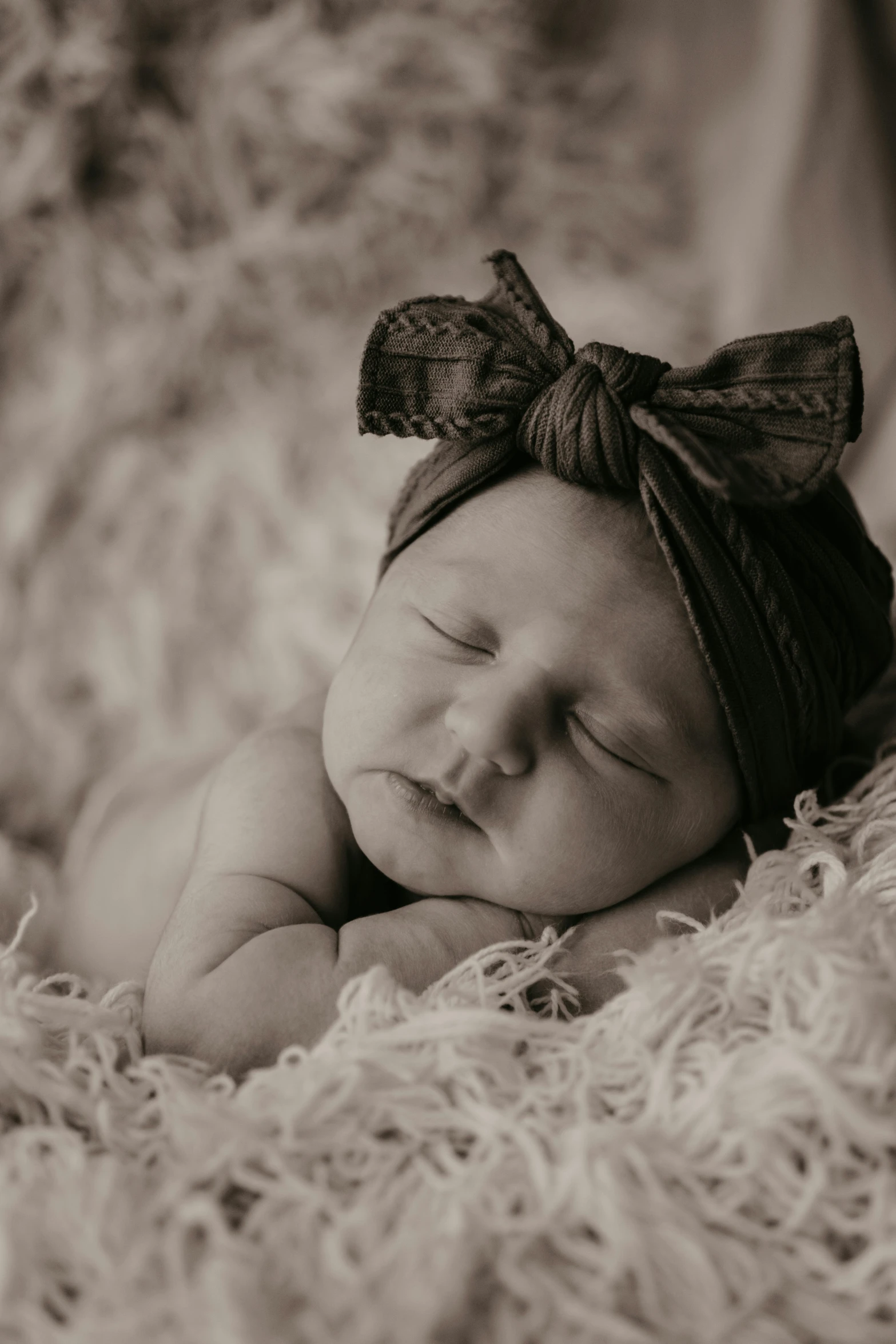 a baby sleeping on its side wearing a hair bow