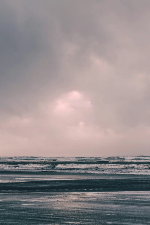 a lone beach umbrella sitting on top of a wet sand beach