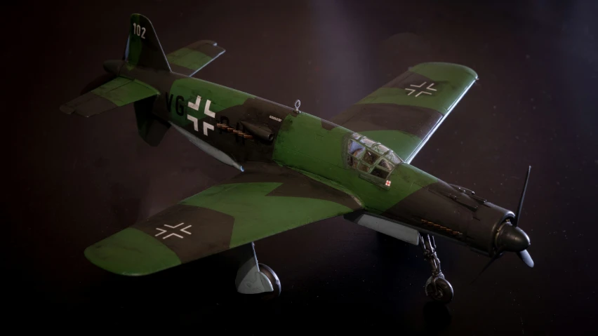 a green and brown plane in flight with its propellers