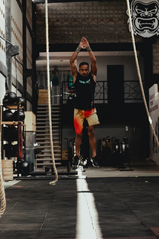 man with hands in the air doing pull ups on ropes