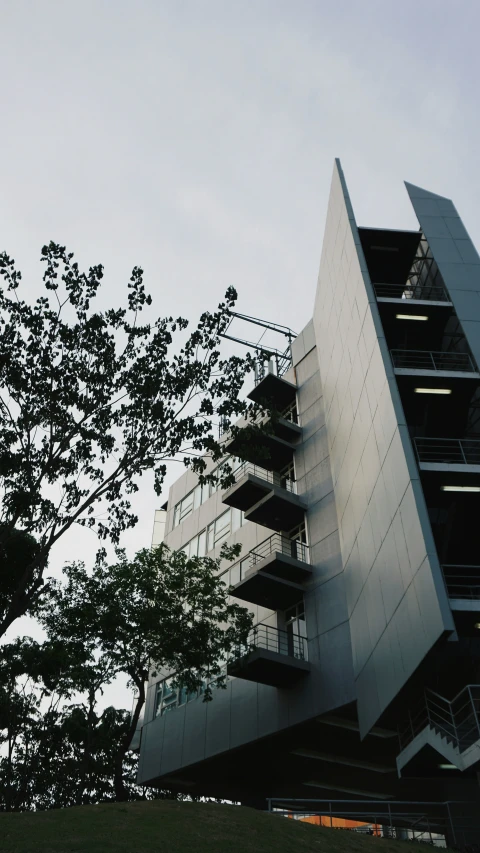 an interesting shaped building sits next to a tree