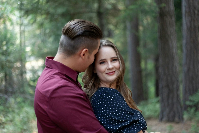 a woman hugs a man while standing in the woods