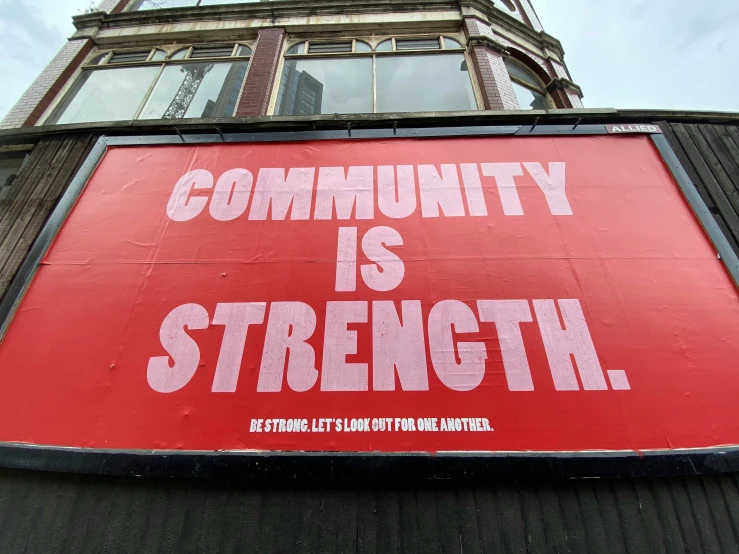 a building with a large red sign on it saying community is strength