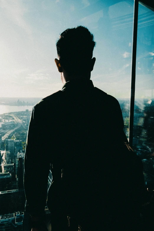 a man is looking out the window at the view of the city