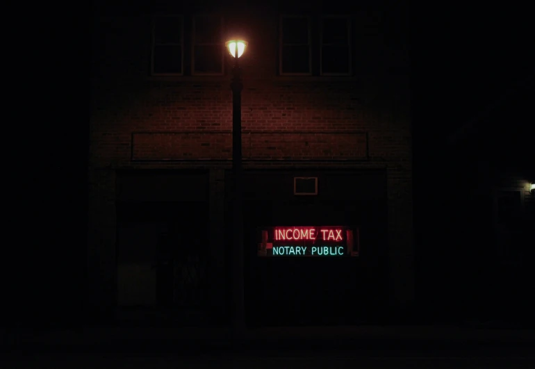 an illuminated neon sign in front of a small building