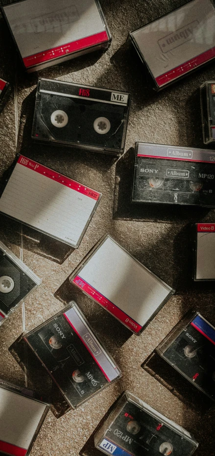 an assortment of cassettes and tape cassette cases laying on the floor