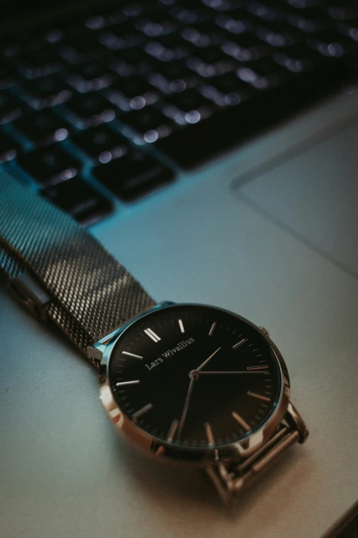 a small wrist watch on top of a table next to a keyboard