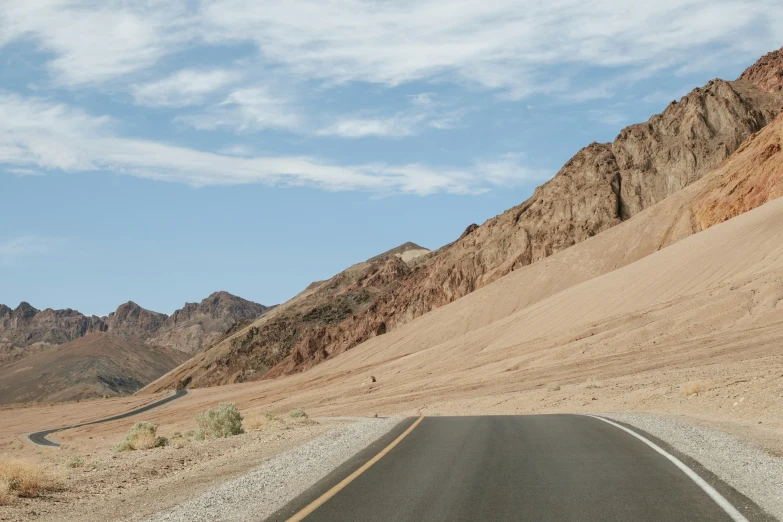 a wide paved road surrounded by sand mountains