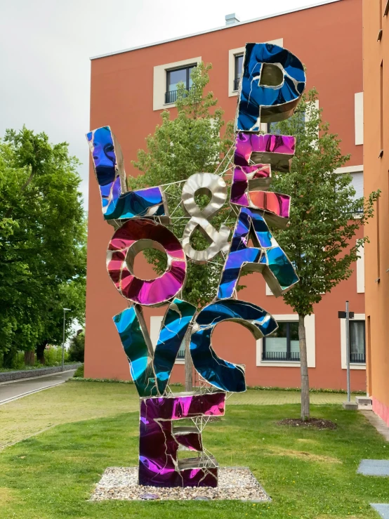 colorful sculptures of letters and numbers on a lawn in front of a multi - colored apartment building