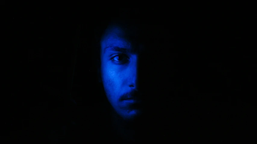 the silhouette of a man with blue glowing makeup