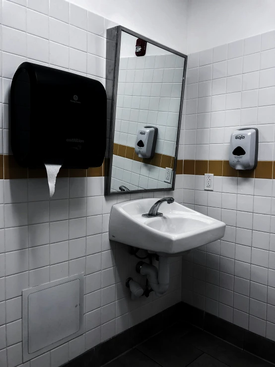 a bathroom sink sitting below a mirror next to a roll of toilet paper