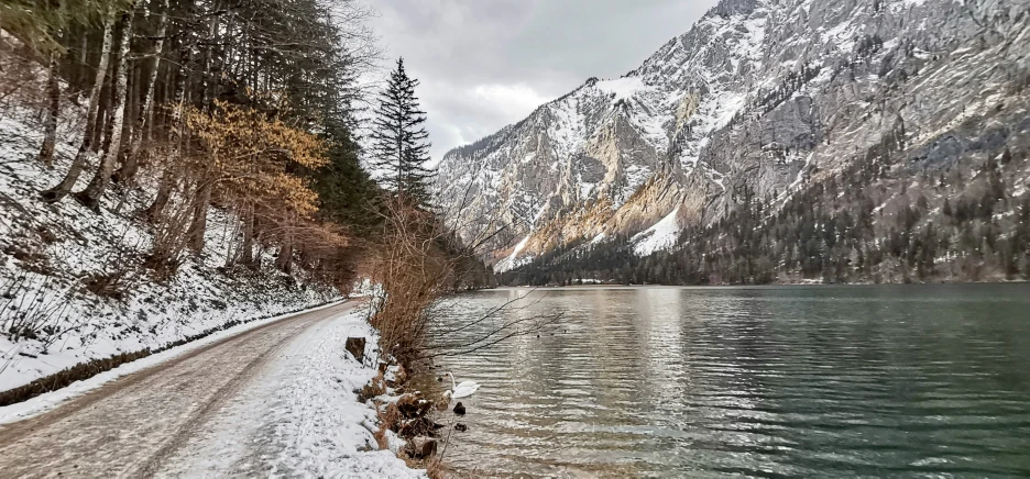 a lake with some snow and mountains in the background