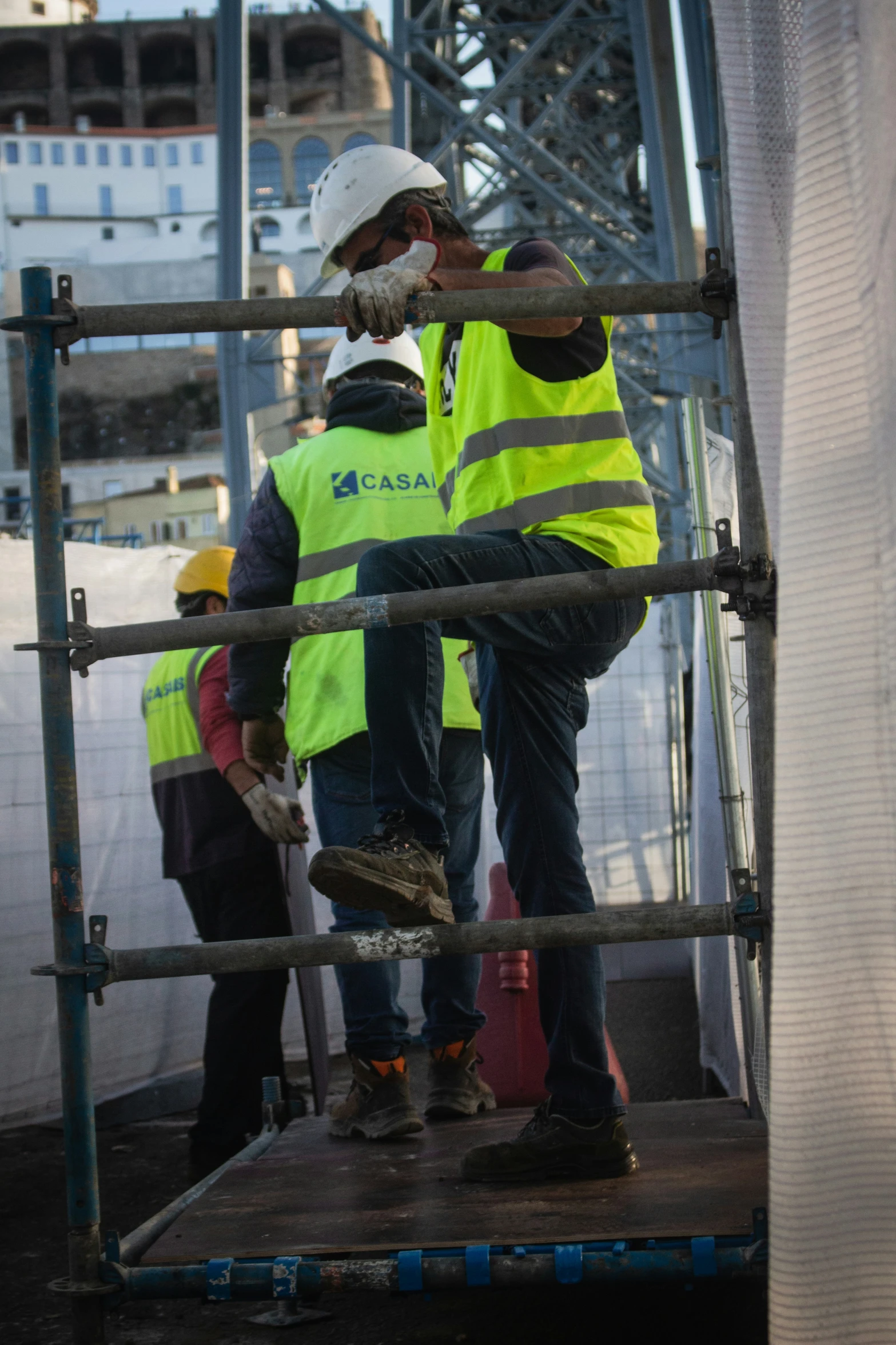 workers in safety vests standing at the base of a bridge