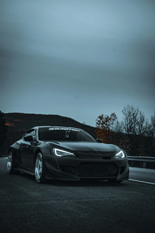 a black sports car sits parked in front of a mountain