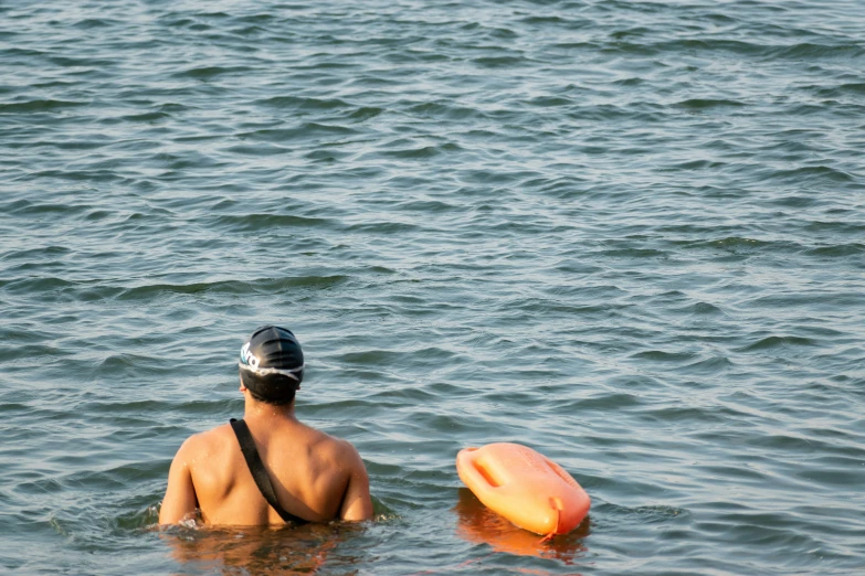 a man is in the water with a hat on and a surfboard in front of him