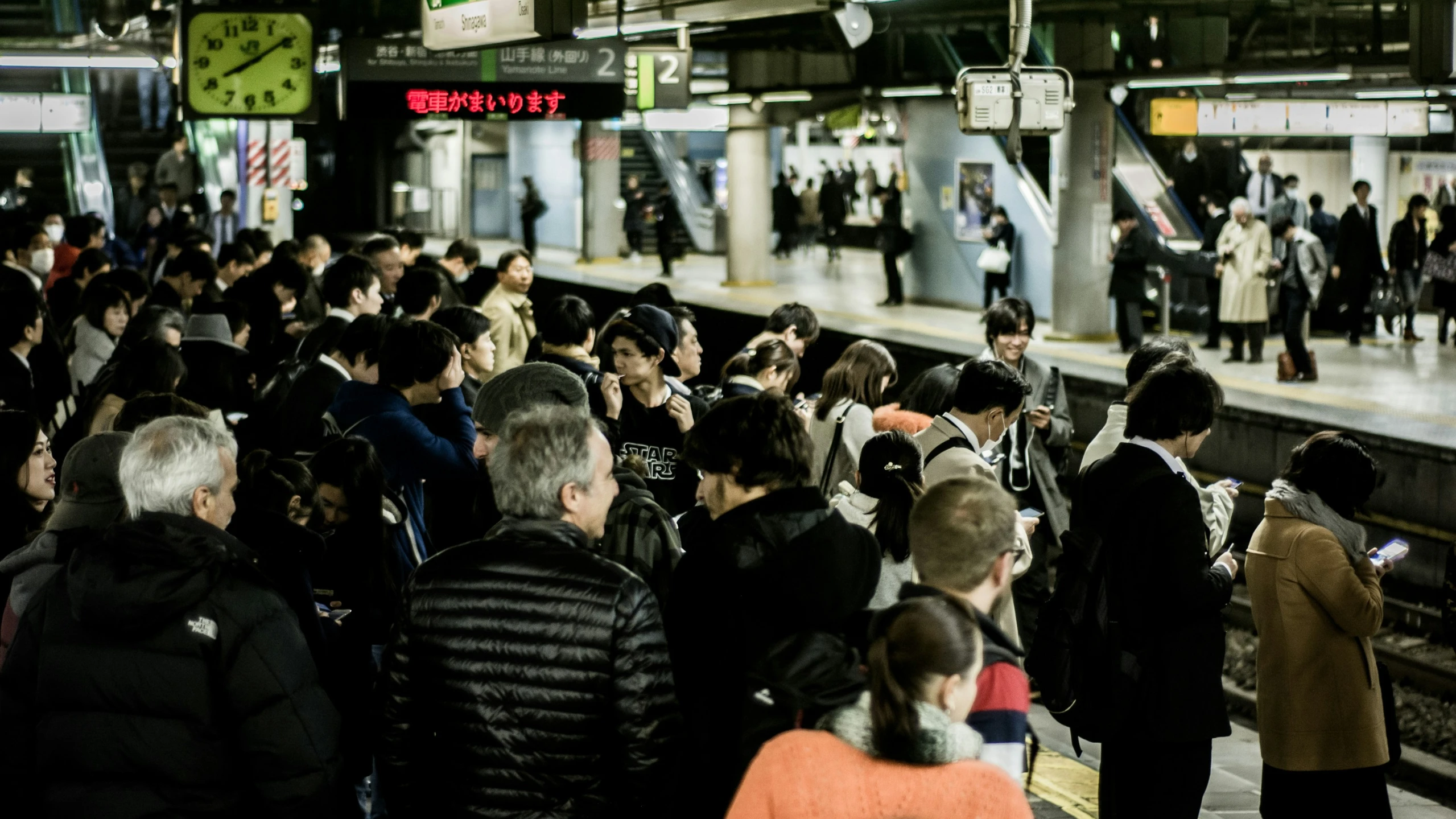 many people standing in a subway station near the platform