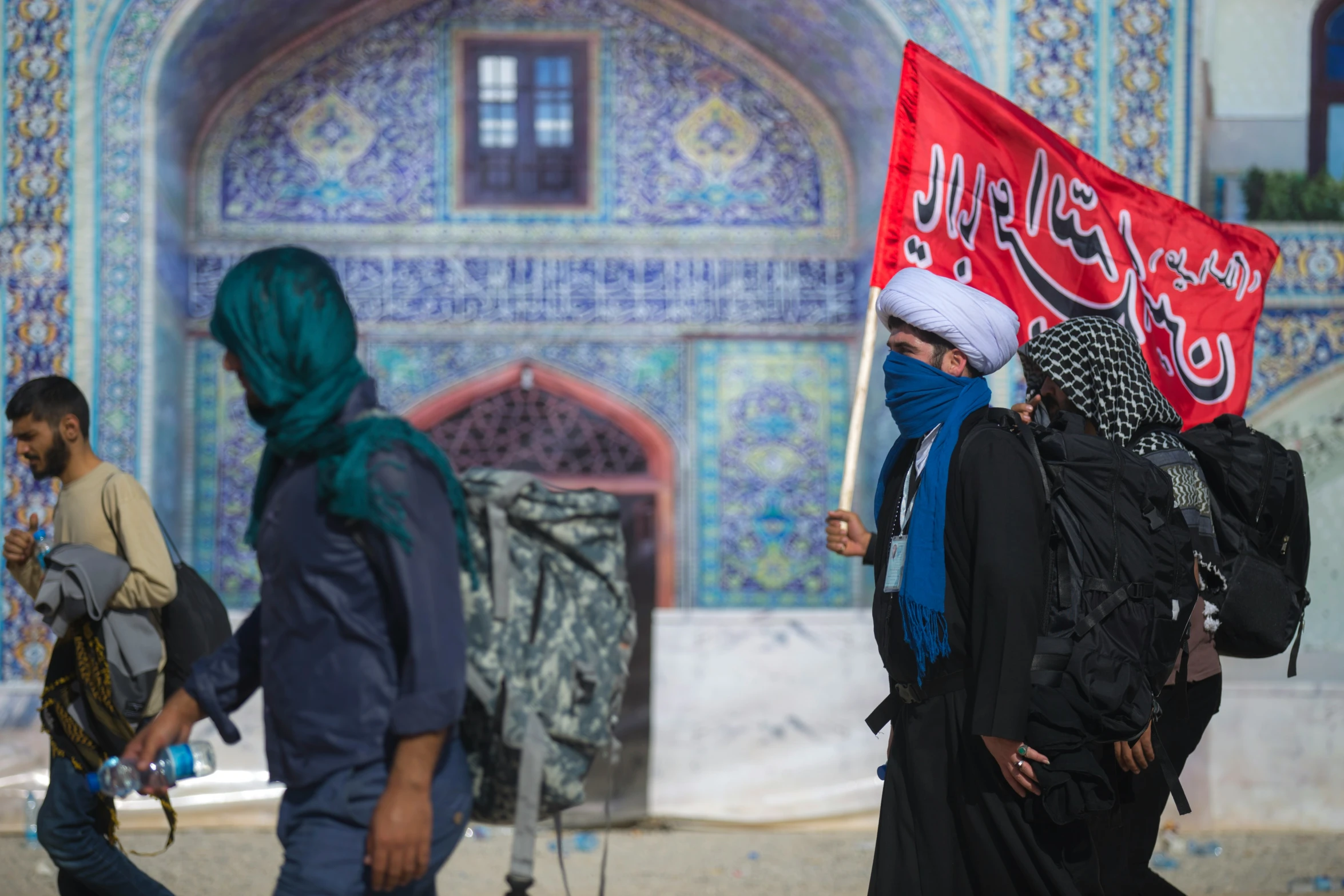 two women carrying a flag and a backpack