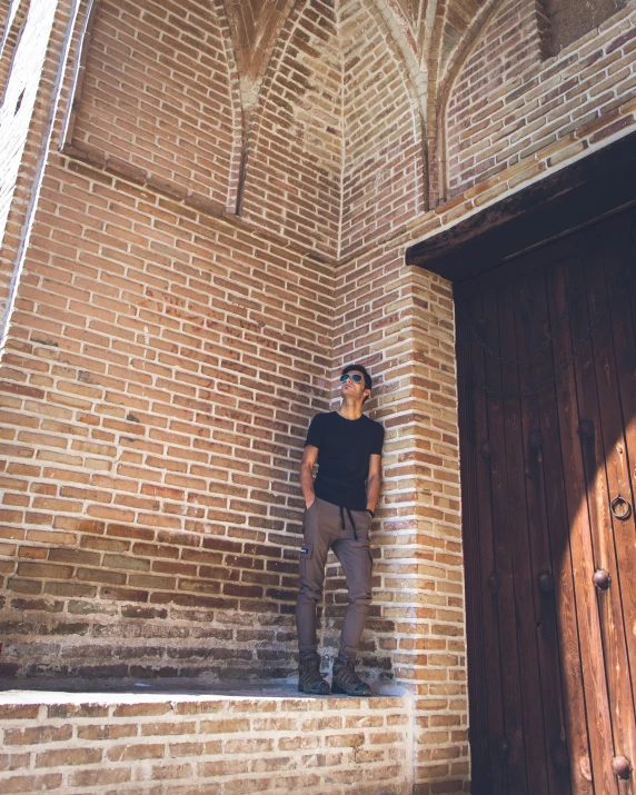 a man leaning against a wall with his hands on his knees