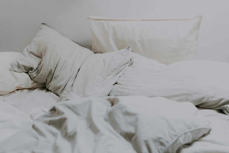 a white bed with two pillows on the pillow