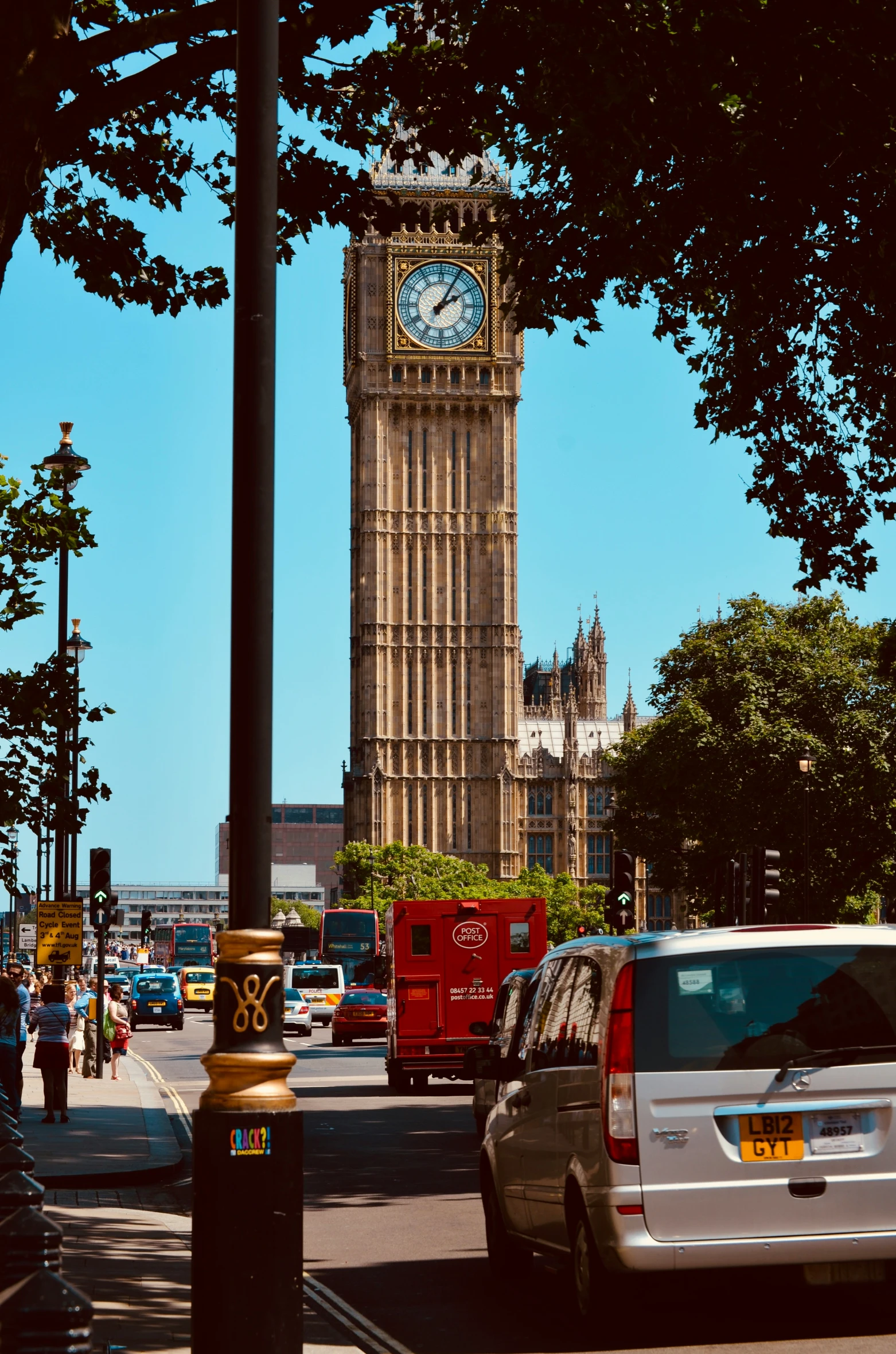 there are cars driving down the street in front of the big ben clock tower