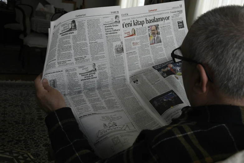 a person that is holding up a large newspaper