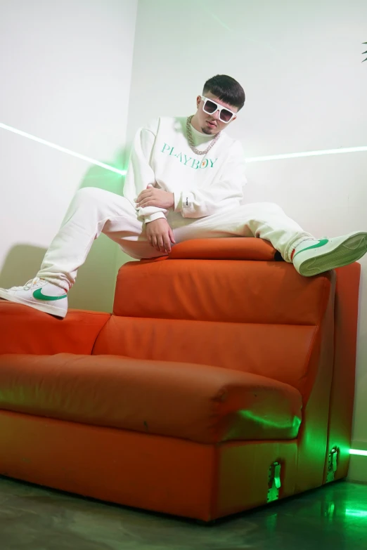 a man is posing on an orange couch