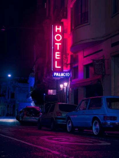 a neon lit el sign and cars are parked at night