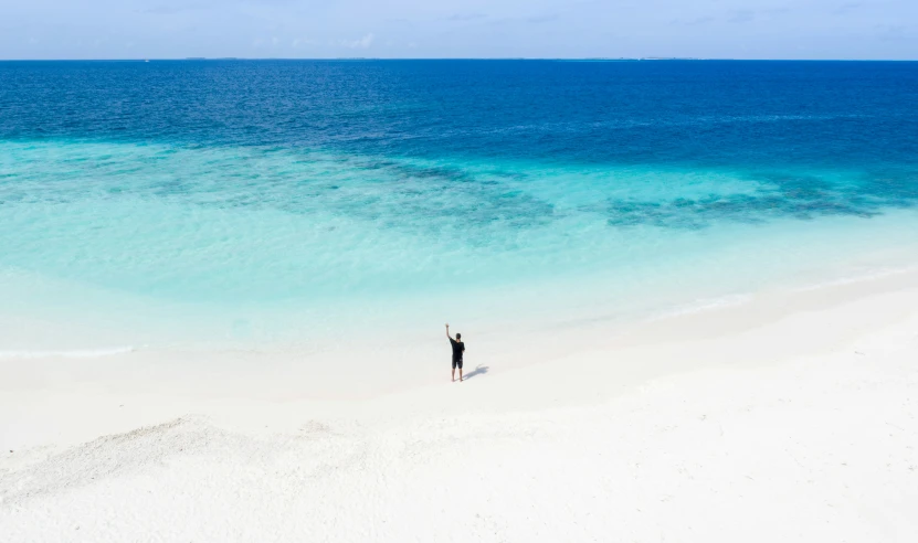 man standing in front of ocean holding his arms in the air