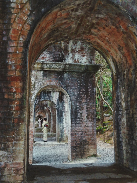 an entrance to an old brick building in the middle of a forest
