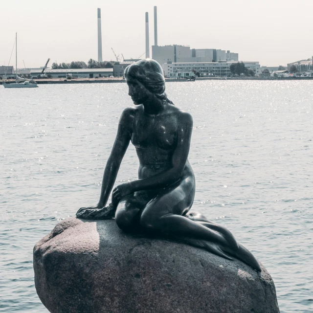 the statue is made up of cement with a body of water in the background