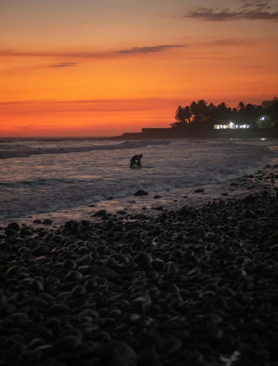 a po of a sunset with a man on the beach walking out towards the ocean