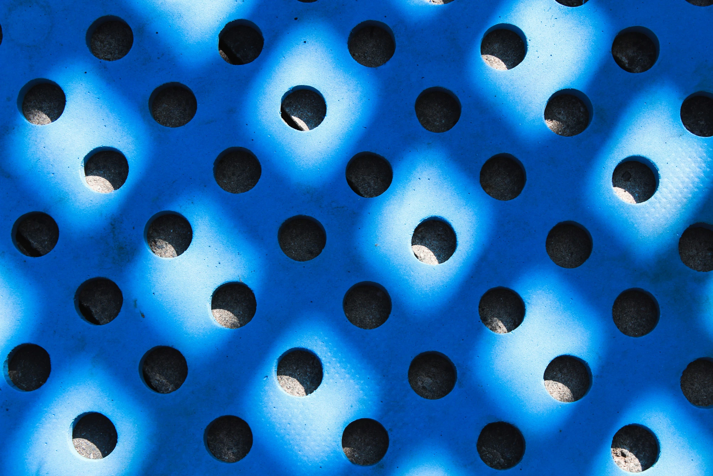 several circles of holes in the background of a blue metal mesh