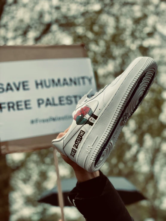 a person holding up a white nike sneaker