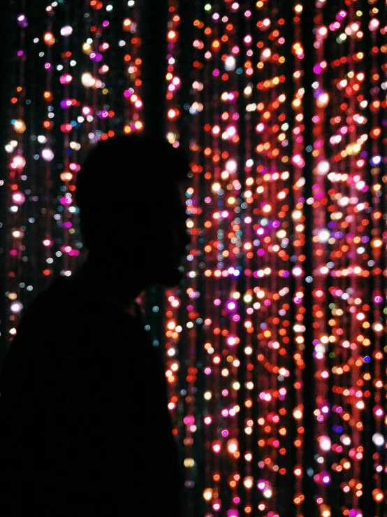 a black silhouette in front of colored lights